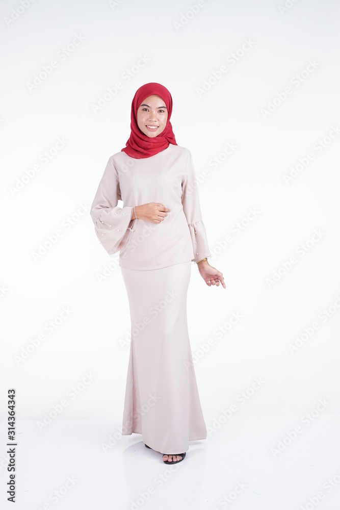 Attractive Muslim female model wearing a cream colored modern kebaya with red hijab, an Asian Muslim traditional dress isolated on white background. Eidul fitri fashion and lifestyle portrait concept.