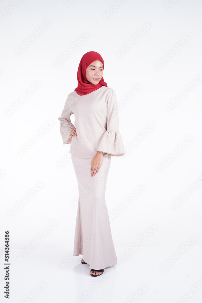 Attractive Muslim female model wearing a cream colored modern kebaya with red hijab, an Asian Muslim traditional dress isolated on white background. Eidul fitri fashion and lifestyle portrait concept. Attractive Muslim female model wearing a cream colored modern kebaya with red hijab, an Asian Muslim traditional dress isolated on white background. Eidul fitri fashion and lifestyle portrait concept.