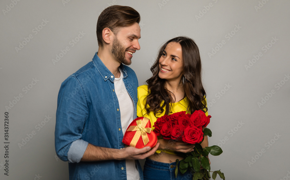 Lovely box. Close-up photo of a handsome man, who is giving a present and a bouquet of red roses to his girlfriend, while looking into her happy eyes. Lovely box. Close-up photo of a handsome man, who is giving a present and a bouquet of red roses to his girlfriend, while looking into her happy eyes.