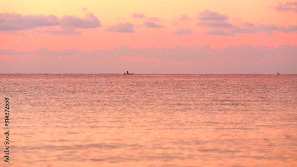 Beautiful cloudy sunset with beautiful pink reflection on the sea surface, with two small boat crossing the horizon Beautiful cloudy sunset with beautiful pink reflection on the sea surface, with two small boat crossing the horizon