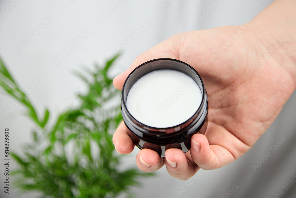 Shea butter in jar, cosmetic product for moisturizing skin. Female hand holds container with white anti-aging smoothing and soothing cream Shea butter in jar, cosmetic product for moisturizing skin. Female hand holds container with white anti-aging smoothing and soothing cream