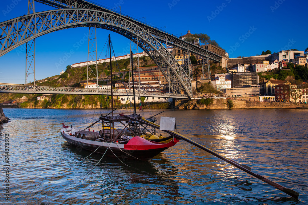Beautiful traditional boat and the Dom Luis I Bridge a metal arch bridge over the Douro River between the cities of Porto and Vila Nova de Gaia in Portugal inaugurated in 1886