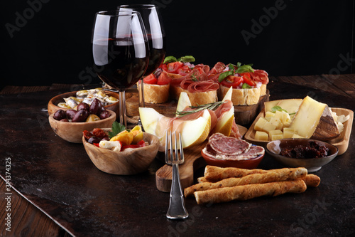 Italian antipasti wine snacks set. Cheese variety  Mediterranean olives  seafood salad  Prosciutto di Parma  tomatoes  anchovy and wine in glasses