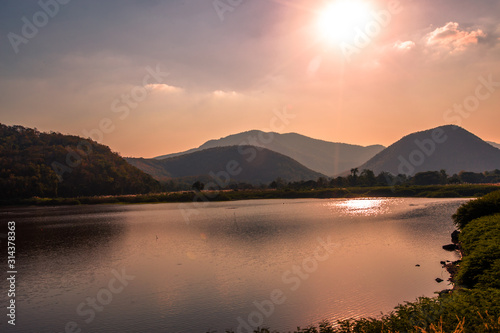 The blurred panoramic nature background of sunlight hitting the lake's surface, grass and wind blowing all the time along the large mountains, ecological beauty and fresh air. © bangprik