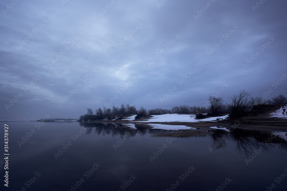 Winter forest reflecting in the Zeya river. Russia