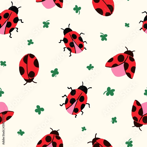 Allover seamless repeat pattern with cute hand-drawn ladybugs of different shapes flying on a cream ground with ditsy green clover leaves tossed. © Pattern_Talent