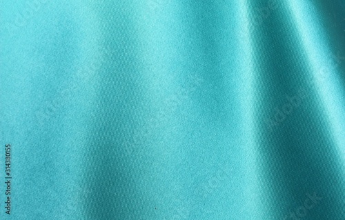 Turquoise satin background. Silk fabric with pleats. Satin, silk or satin create a beautiful drape. Fashion design, background. photo
