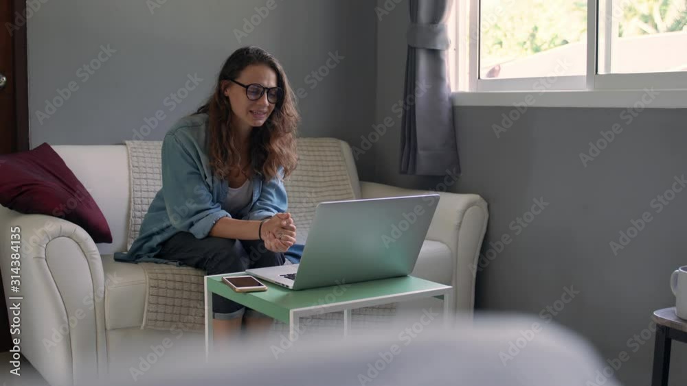A young woman with a laptop sitting on a sofa in the living room holds an online consultation. Distance learning. A young woman with a laptop sitting on a sofa in the living room holds an online consultation. Distance learning.