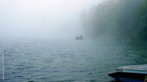 Fisherman in boat is fishing on a foggy Minnesota lake in early morning. photo