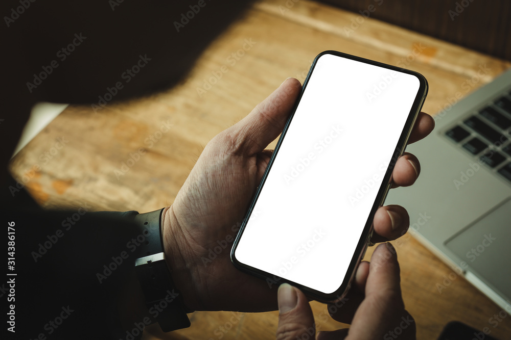Mockup image blank white screen cell phone.man hand holding texting using mobile on desk at office.background empty space for advertise text.people contact marketing business,technology 