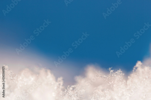 Background from crystal clear real snowflakes in blue shades in macro with copy space for your text. Christmas and New Year background frame with a border of natural ice snowflakes close-up.