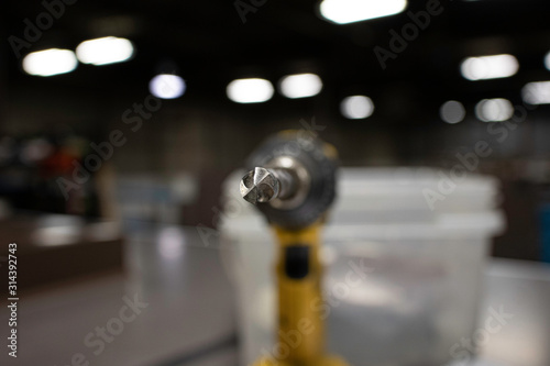 Hand drill in factory workshop with selective focus on the drill bit