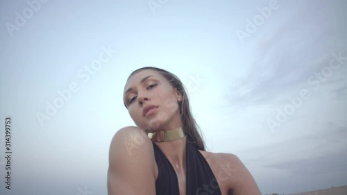 Portrait of dancer young dark-haired woman wearing black swim bodysuit in the desert. Portrait of a young fashion model in sunset light.