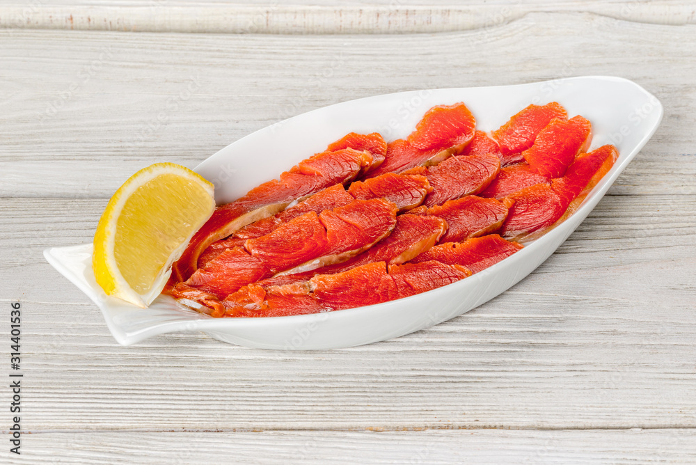 Sliced sockeye salmon on a white plate with lemon Sliced sockeye salmon on a white plate with lemon