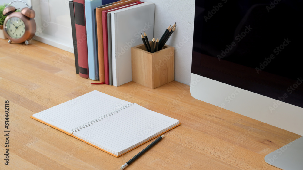 Close up view of modern workspace with note book, computer and office supplies on wooden table background Close up view of modern workspace with note book, computer and office supplies on wooden table background