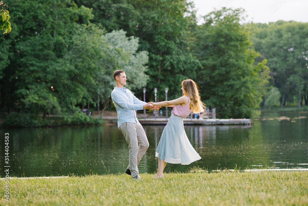 A romantic couple in love holding hands and spinning on the shore of the lake A romantic couple in love holding hands and spinning on the shore of the lake