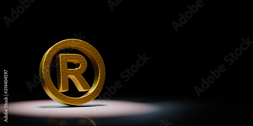 Golden Trademark Symbol Spotlighted on Black Background photo