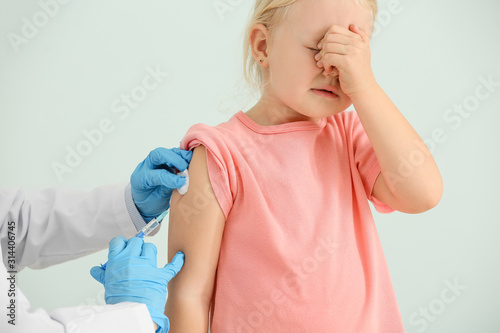 Doctor vaccinating little g...