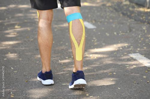 Sporty man with physio tape applied on leg outdoors