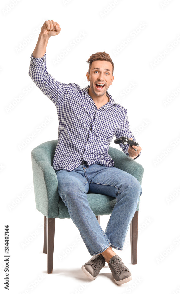 Happy man playing video games while sitting in armchair on white background
