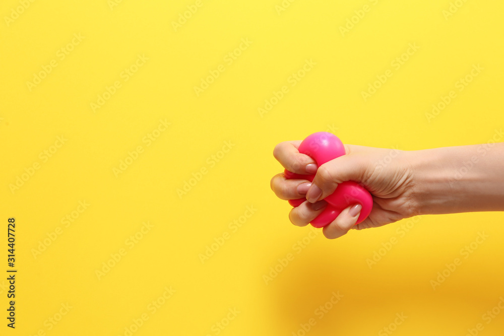 Female hand squeezing stress ball on color background - obrazy, fototapety, plakaty 