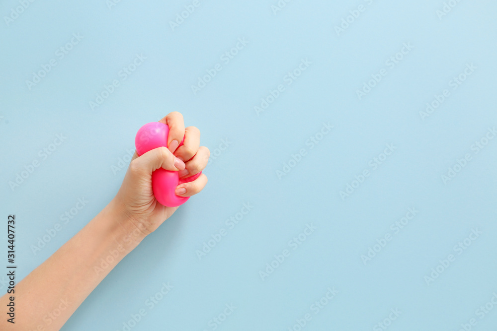 Female hand squeezing stress ball on color background Female hand squeezing stress ball on color background
