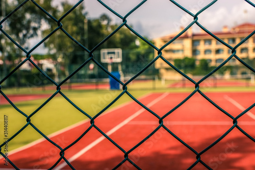 Open air tennis and basketball court or field behind the metal fence. Artificial deck. Forbidden Method or inaccessible tennis field.