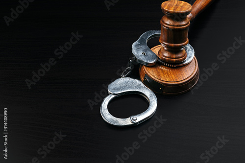Judge gavel with handcuffs on wooden table