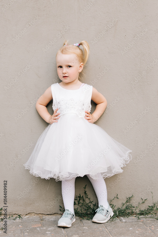 Happy baby girl in white dress on grey background Happy baby girl in white dress on grey background
