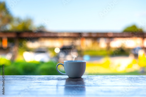 A white cup of coffee with smoke on blurred estate scenic background.Coffee for good morning time with nature background.