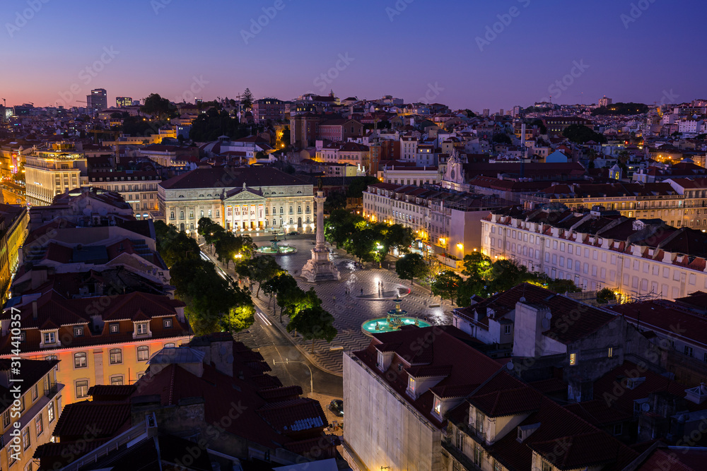 Obraz premium View of the Rossio Square (Praca do Rossio) in the Baixa district and beyond from above in Lisbon, Portugal, in the evening.