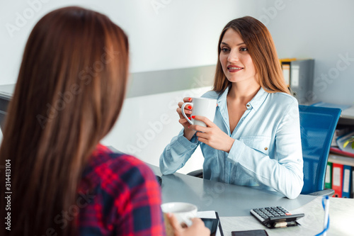 women sitting in the office during coffee break and holding a cup