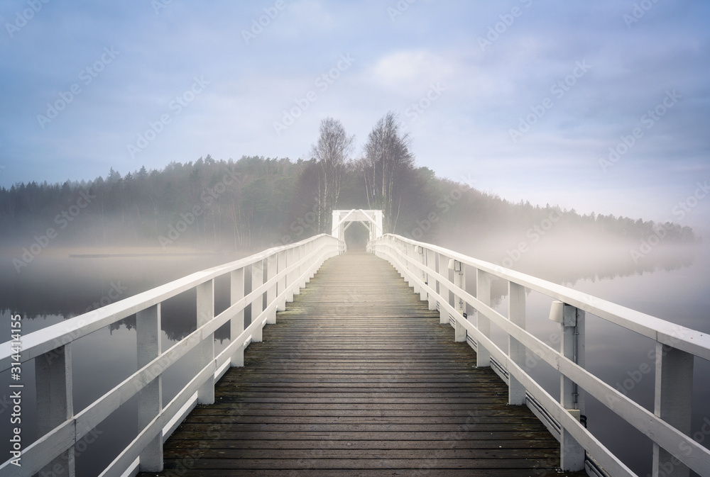 Old wooden bridge with mist haze mood and calm air at autumn morning in Finland