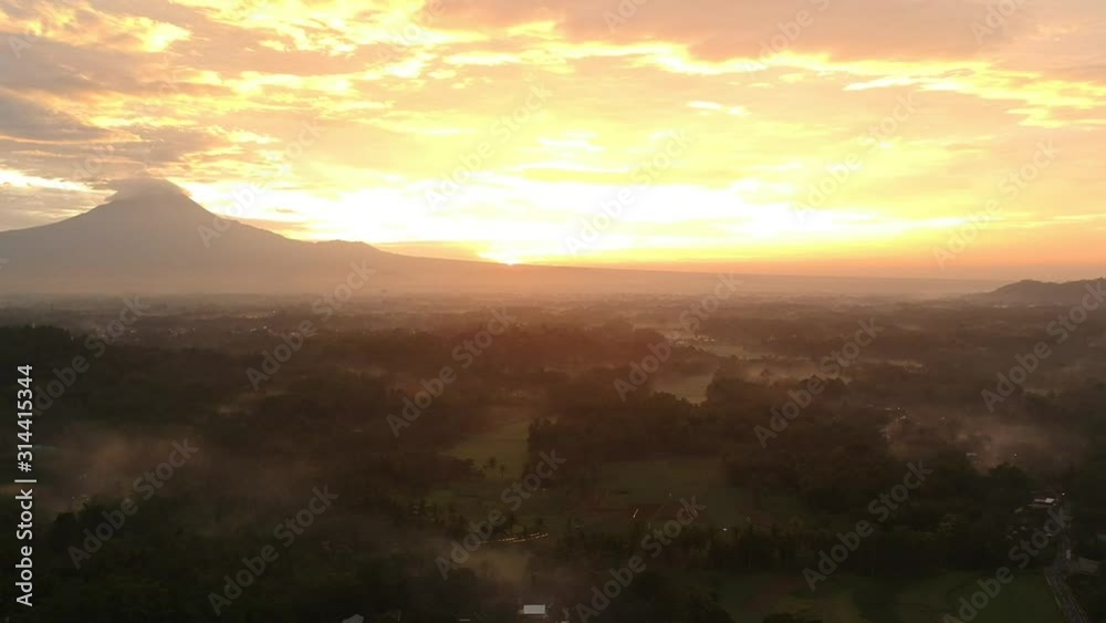 JAVA Mount Vulcano Merapi during stunning misty sunrise borobodur in background orange sun captured with drone