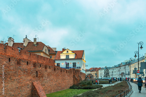 16th century Warsaw Barbican, element of the Warsaw defensive walls. Illuminated street with walking people, Poland.