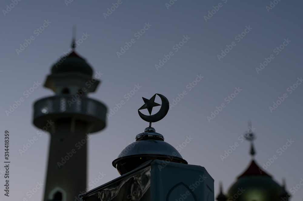 logo moon and star stainless with blur The central mosque of Pattani Province  in background.concept for postcard and texture background.symbol and place for prey for islamic people