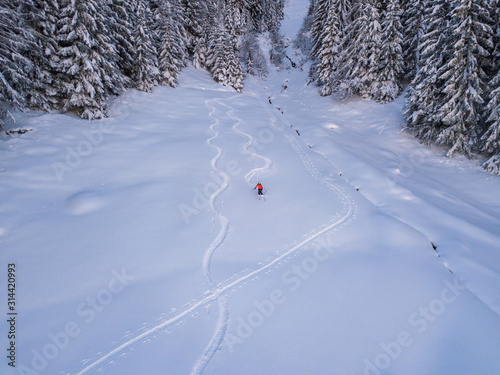 Obraz na plátně Aerial view of backcountry freeride skier leaving traces in powder snow