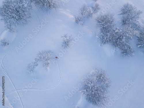 Aerial view of backcountry freeride skier leaving traces in powder snow. Concept of backcountry mountaineering.