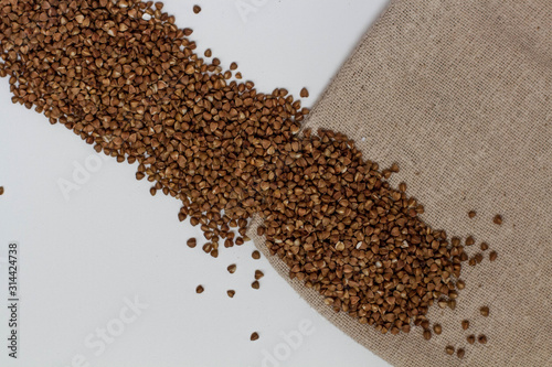 scattered Buckwheat porridge on a White background with a natural fabric. cereals and cereals. The view from the top. Space for text. delicious and healthy food and nutrition. vitamins for humans.