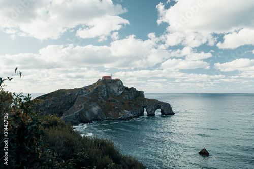 Scenic view of famous island in the basque country against cloudy sky