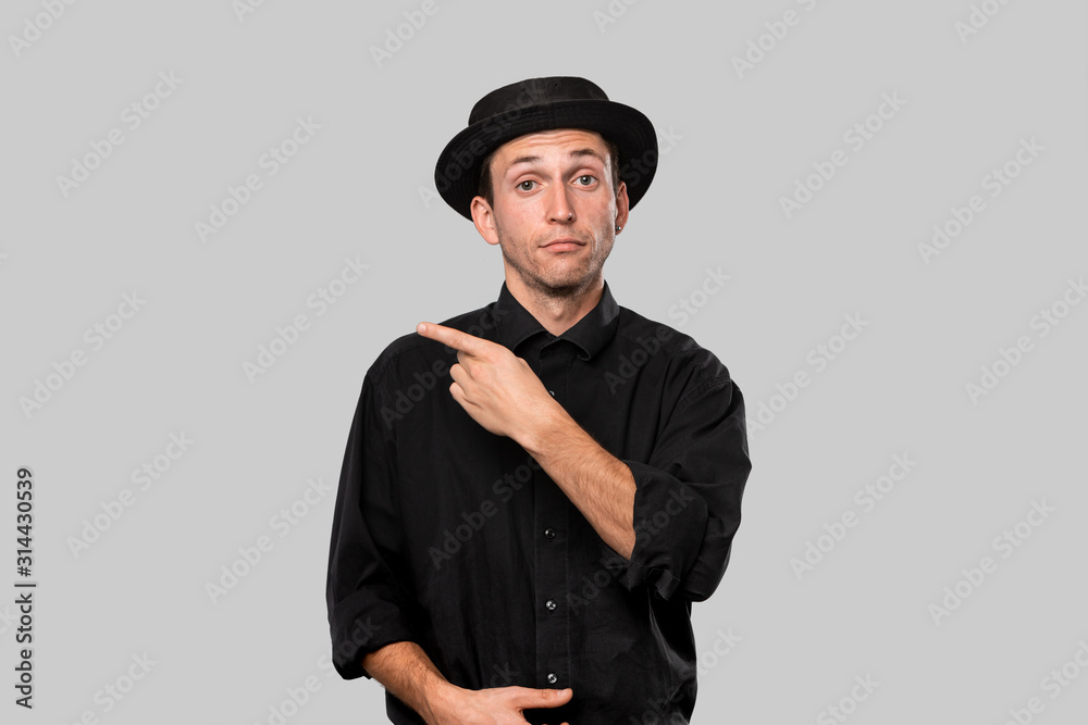 Portrait of a stylish handsome man in a black shirt and pork pie hat pointing at the copy space Portrait of a stylish handsome man in a black shirt and pork pie hat pointing at the copy space