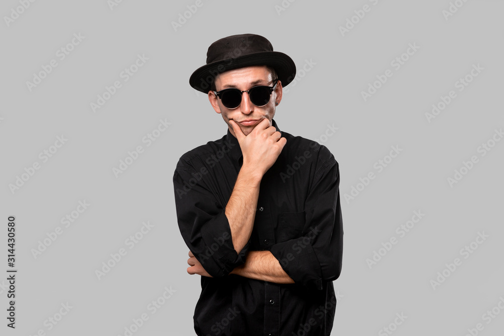 Stylish handsome man a black shirt and pork pie hat isolated over grey background Stylish handsome man a black shirt and pork pie hat isolated over grey background