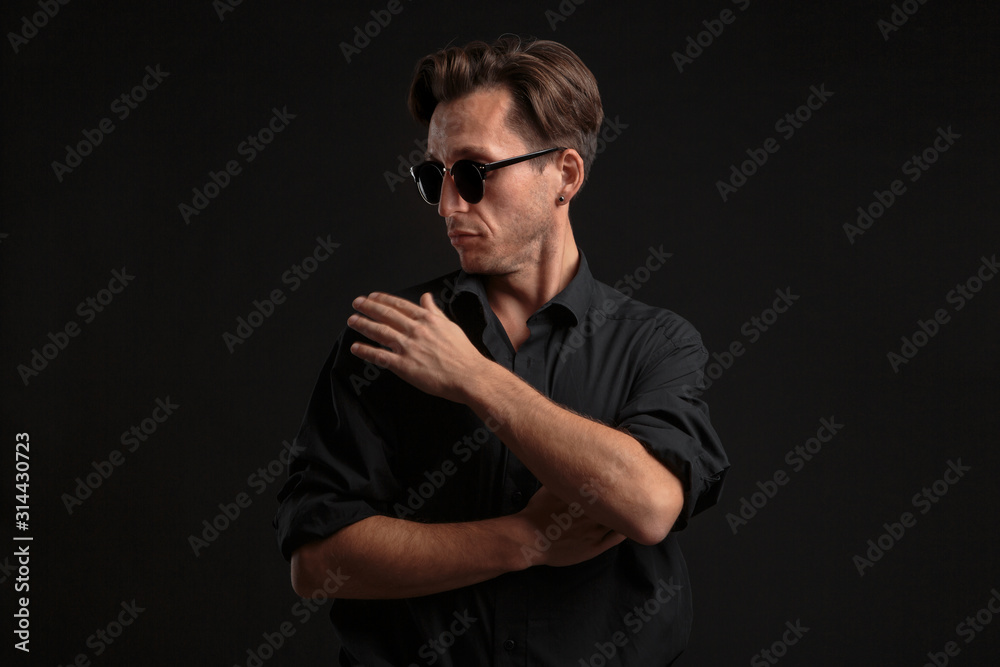 Confident stylish man in black eyeglasses isolated over black background.