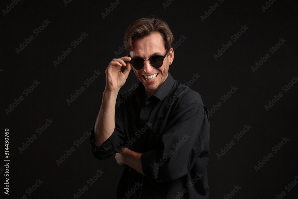 Confident stylish man in black eyeglasses isolated over black background. Confident stylish man in black eyeglasses isolated over black background.