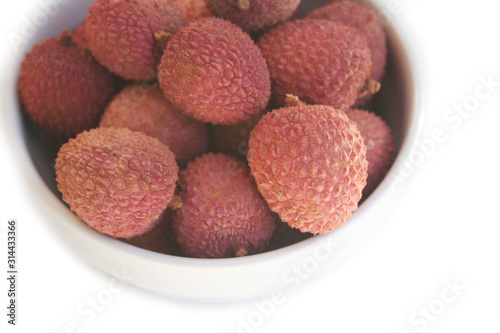 Fresh ripe litchi or lychee fruits in a bowl isolated on white background. Litchi chinensis fruit