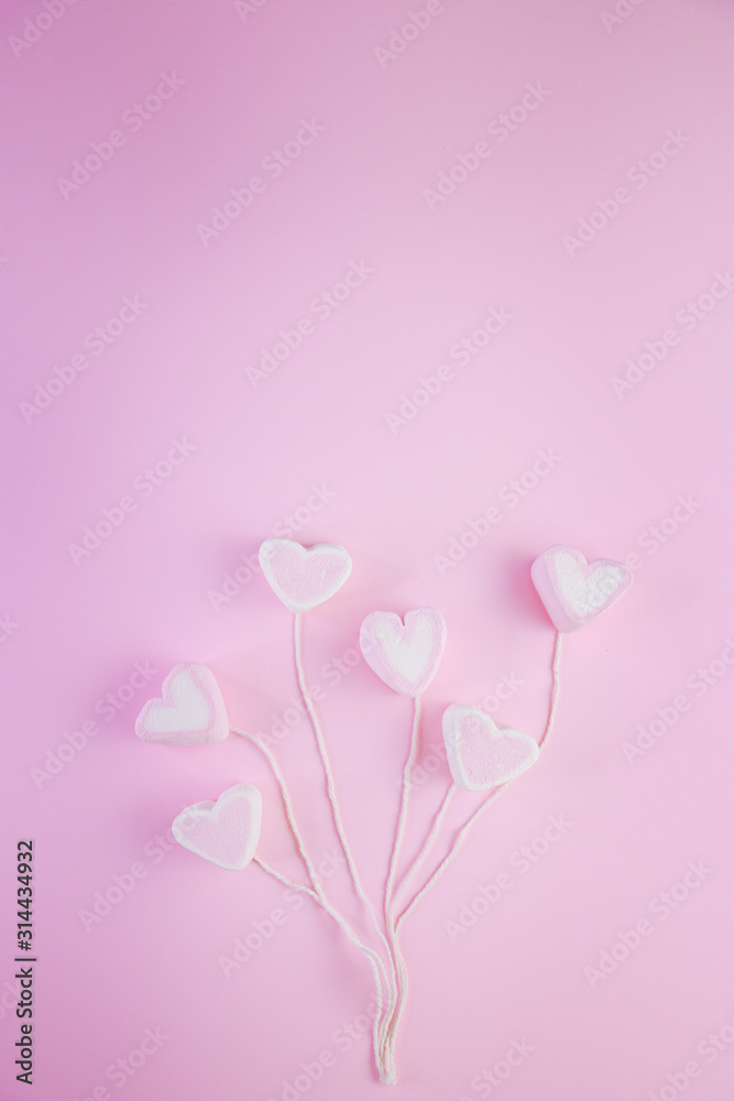 Pastel Valentine background is made of marshmallow souffle in the form of hearts on a string on a pink background. Valentine's day concept with copy space Pastel Valentine background is made of marshmallow souffle in the form of hearts on a string on a pink background. Valentine's day concept with copy space