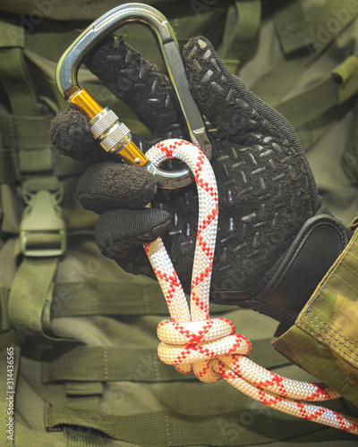 hand in a black glove holds a climbing rope tied in a knot 