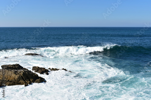 Seascape with waves breaking against the rocks and blue sky. Galicia, Spain. © JB