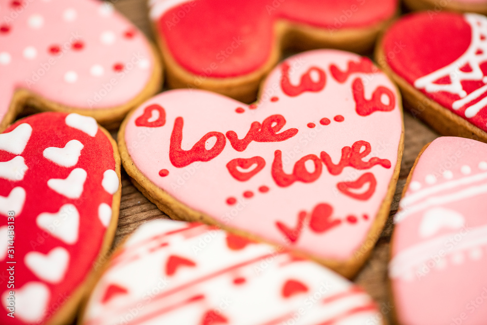 Gingerbread hearts festive on Valentine's Day on a wooden background. Delicious and sweet, covered with icing with a beautiful pattern, handmade. The view from the top. Macro. Gingerbread hearts festive on Valentine's Day on a wooden background. Delicious and sweet, covered with icing with a beautiful pattern, handmade. The view from the top. Macro.