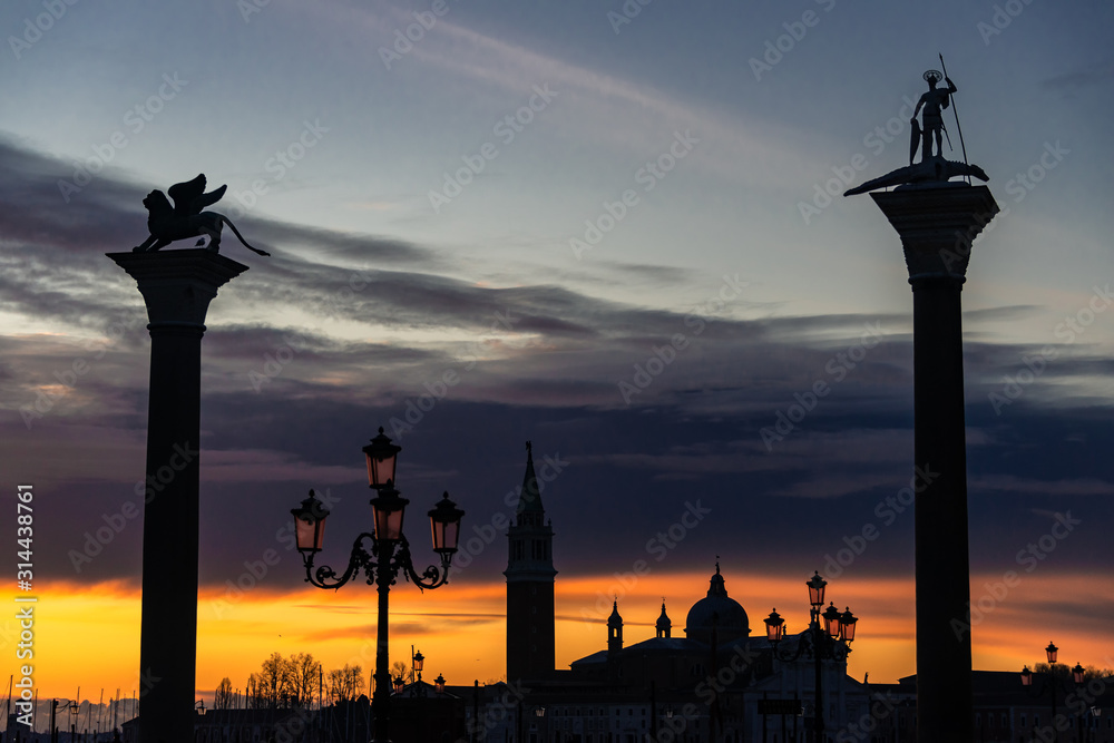 Breathtaking sunrise view of empty San Marco square in Venice on orange sky and San Giorgio Maggiore silhouette background Breathtaking sunrise view of empty San Marco square in Venice on orange sky and San Giorgio Maggiore silhouette background